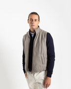 A refined take on the classic gilet, this sleeveless vest is crafted from a premium wool-blend fabric in a warm greige melange. Subtly padded for lightweight insulation without bulk, it layers effortlessly over knitwear or a collared shirt for a polished smart-casual look.

Featuring a stand collar, full-length zip fastening with a gunmetal pull, and clean jetted front pockets, the cut is slim and tailored — designed to sit neatly under a jacket or wear alone as an outer layer.