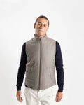 A refined take on the classic gilet, this sleeveless vest is crafted from a premium wool-blend fabric in a warm greige melange. Subtly padded for lightweight insulation without bulk, it layers effortlessly over knitwear or a collared shirt for a polished smart-casual look.

Featuring a stand collar, full-length zip fastening with a gunmetal pull, and clean jetted front pockets, the cut is slim and tailored — designed to sit neatly under a jacket or wear alone as an outer layer.