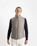 A refined take on the classic gilet, this sleeveless vest is crafted from a premium wool-blend fabric in a warm greige melange. Subtly padded for lightweight insulation without bulk, it layers effortlessly over knitwear or a collared shirt for a polished smart-casual look.

Featuring a stand collar, full-length zip fastening with a gunmetal pull, and clean jetted front pockets, the cut is slim and tailored — designed to sit neatly under a jacket or wear alone as an outer layer.