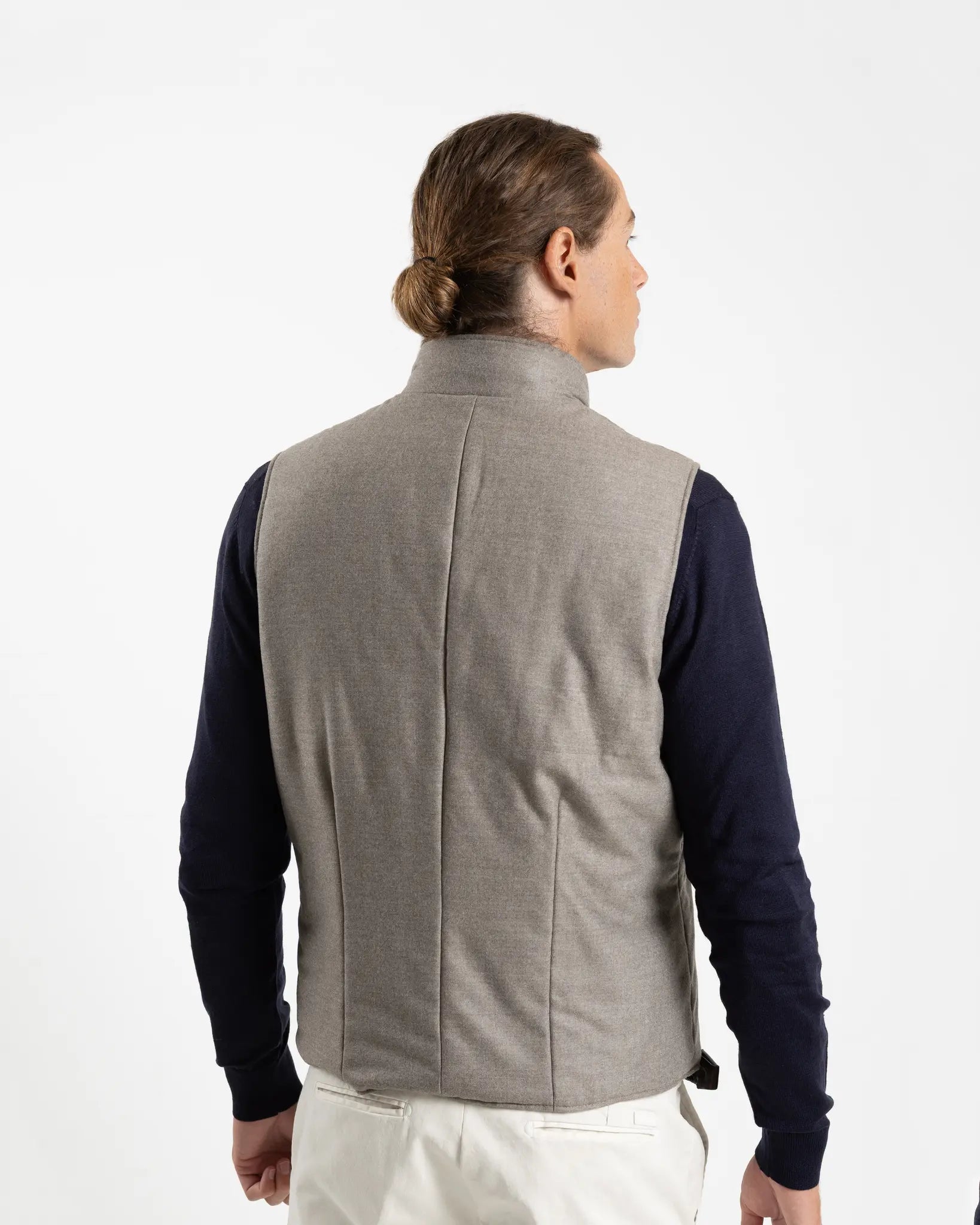 A refined take on the classic gilet, this sleeveless vest is crafted from a premium wool-blend fabric in a warm greige melange. Subtly padded for lightweight insulation without bulk, it layers effortlessly over knitwear or a collared shirt for a polished smart-casual look.

Featuring a stand collar, full-length zip fastening with a gunmetal pull, and clean jetted front pockets, the cut is slim and tailored — designed to sit neatly under a jacket or wear alone as an outer layer.