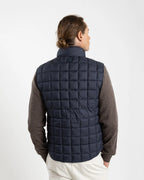 A clean, no-nonsense gilet built for layering. The box-quilt construction gives it structure and warmth, while the streamlined full-zip closure and high stand collar block the wind without adding bulk. Two side slip pockets sit flush with the quilting — functional without interrupting the clean lines.