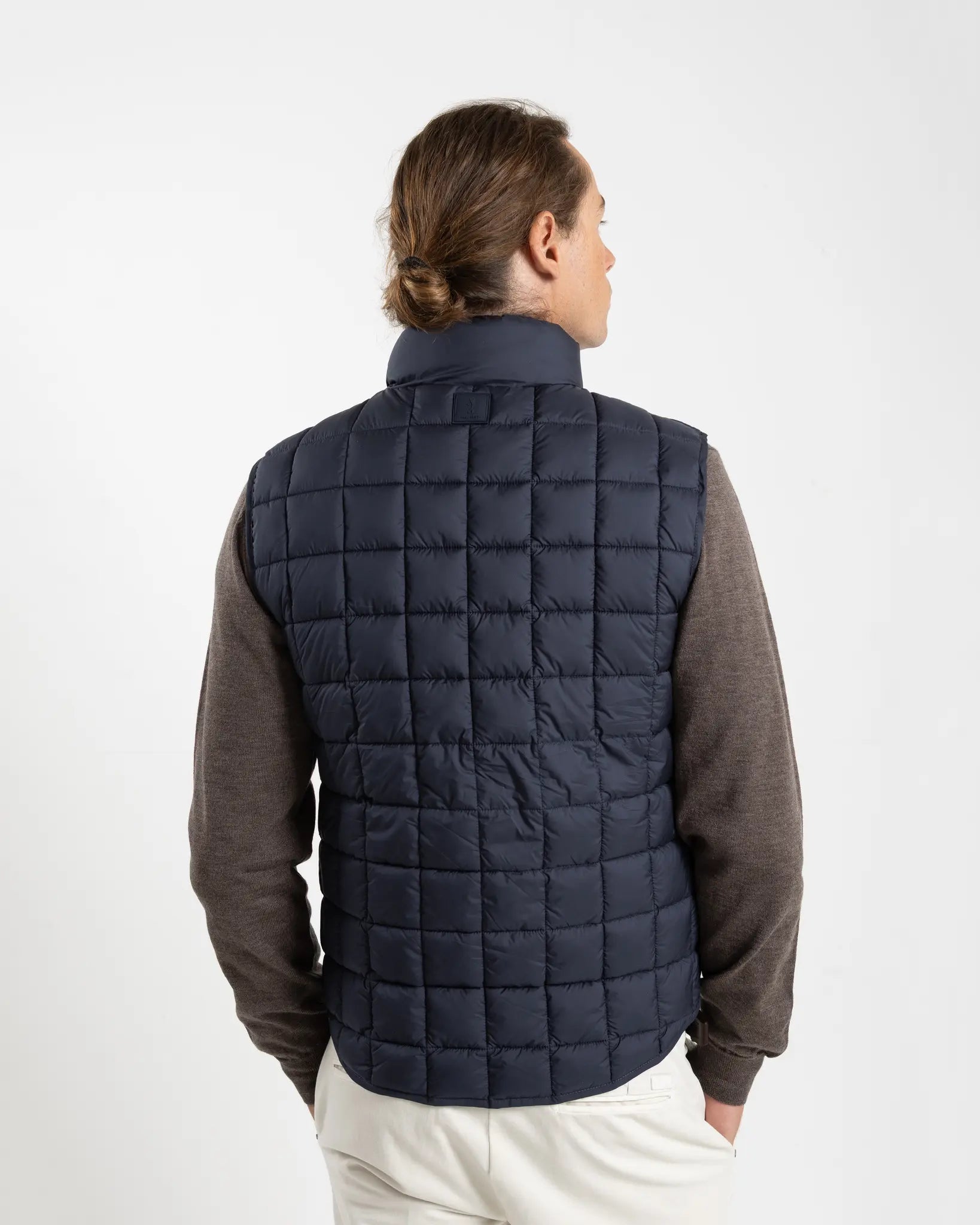 A clean, no-nonsense gilet built for layering. The box-quilt construction gives it structure and warmth, while the streamlined full-zip closure and high stand collar block the wind without adding bulk. Two side slip pockets sit flush with the quilting — functional without interrupting the clean lines.