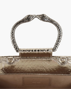 Clutch in precious silver-colored snake leather with round rigid body and removable leather strap.Brass bracelet, iconic accessory of the Tramontano archive handcrafted.Top closure with double magnets.

Microfiber lining. Accessories in gold finish.

Material: Snake Elaphe
Dimensions: 20x11x7 cm