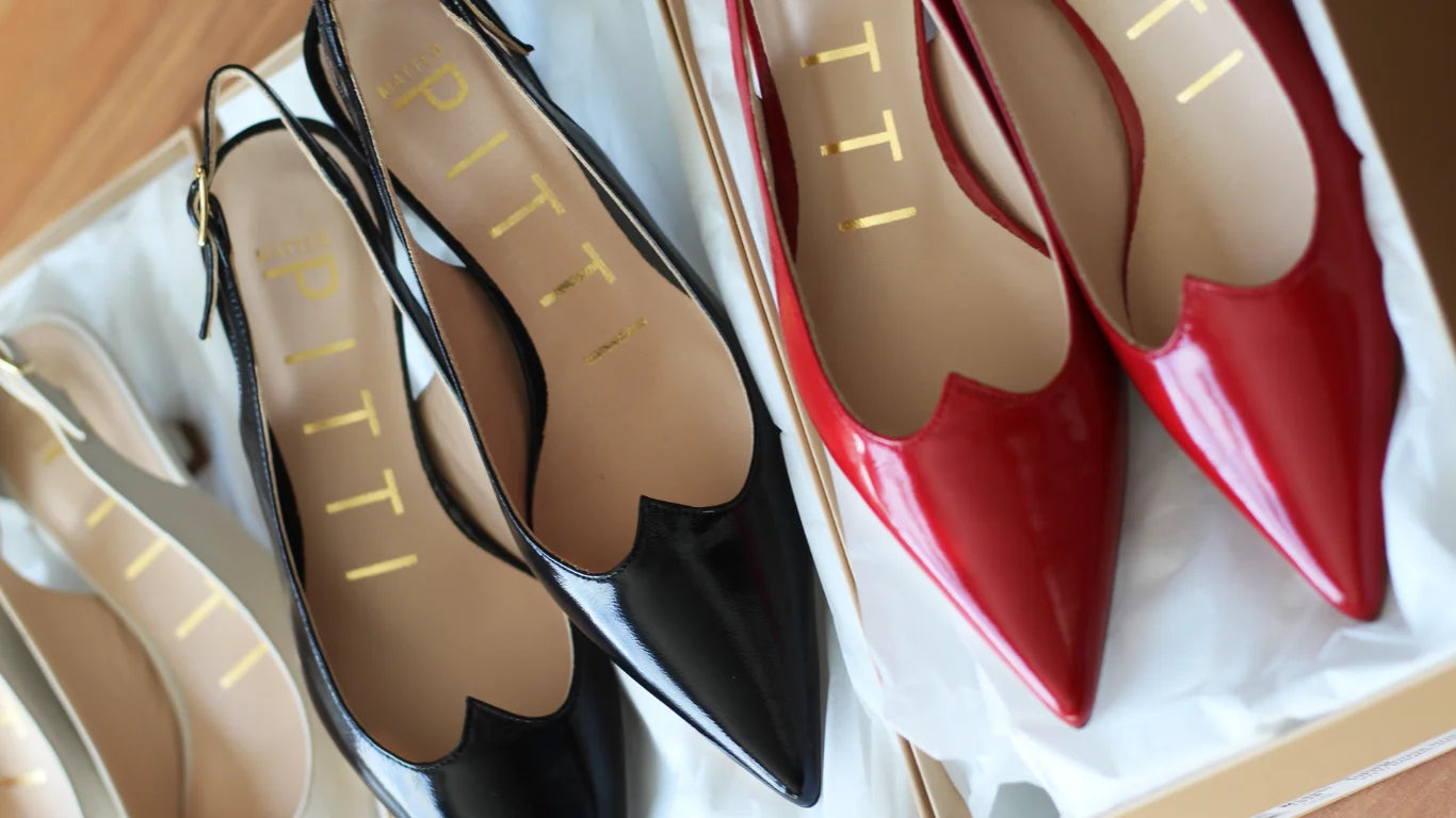 Close-up of Italian-made Aliverti women’s heels in glossy red, black, and beige leather, neatly arranged in boxes on a wooden surface — representing Aliverti’s craftsmanship and timeless sophistication.