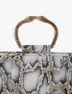 Clutch in precious snake leather with rounding rigid body and removable leather crossbody.Brass bracelet, iconic accessory of the Tramontano archive handcrafted.Top closure with double magnets. Microfiber lining. Accessories in gold finish. Material: Snake ElapheDimensions: 31x12x8 cm