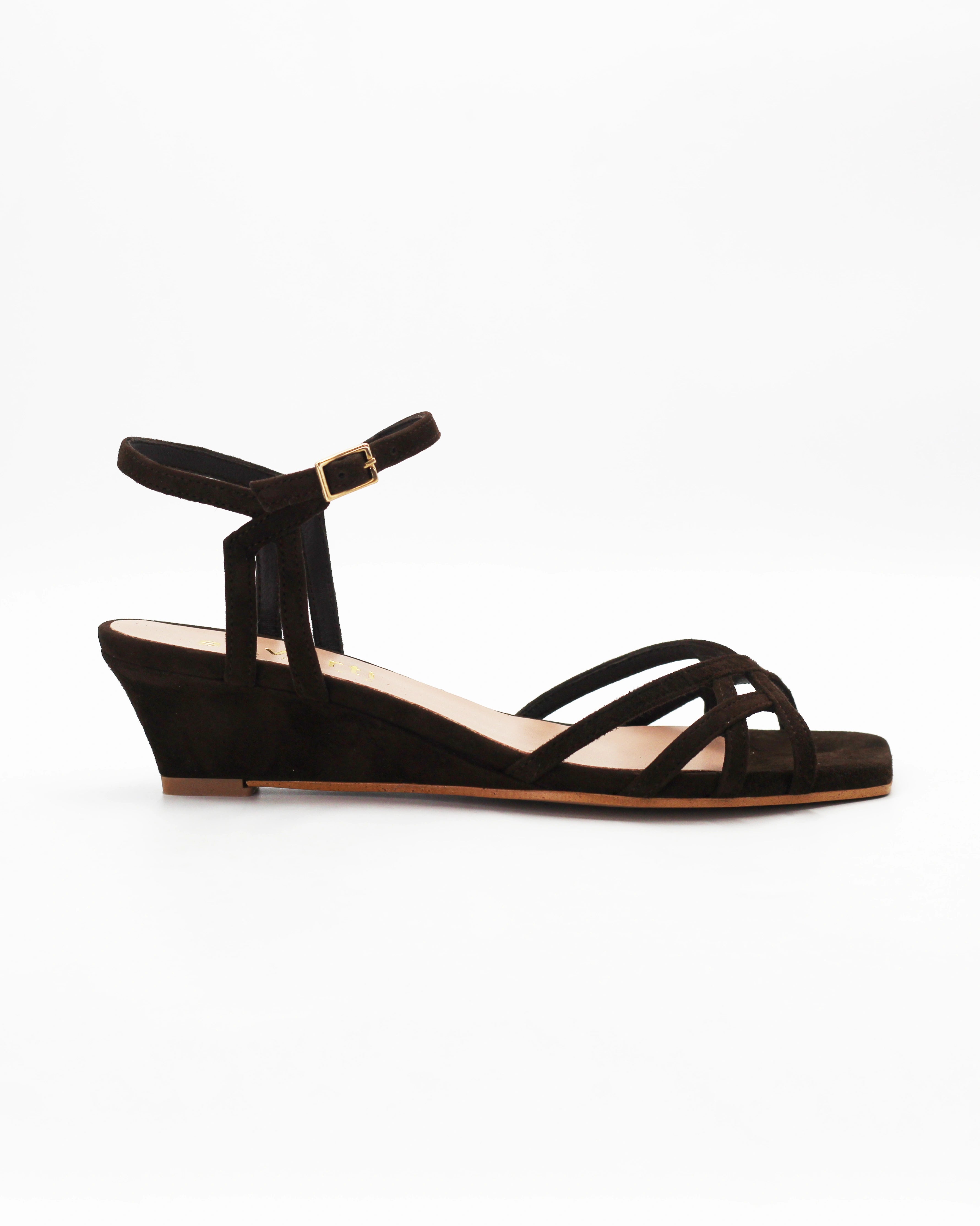 Shop the LYA8 wedge heel sandal in dark brown suede calf leather. Italian-made with a woven strap detail, adjustable ankle strap, and rubber sole. Elevated summer elegance.