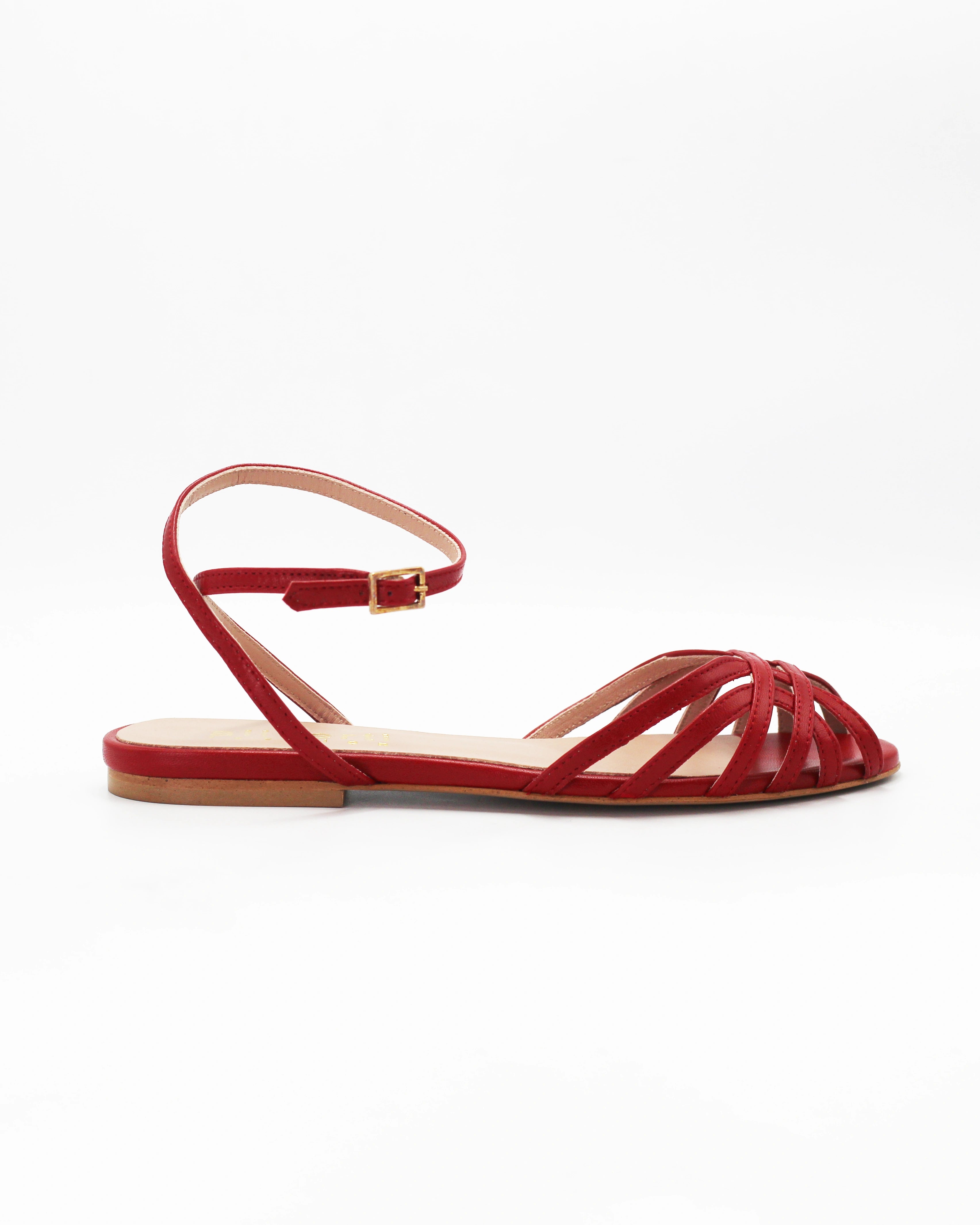 Shop the CIRA5 flat lattice sandal in red calf leather. Italian-made with a woven strap detail, adjustable ankle strap, and rubber sole. Effortless summer elegance.