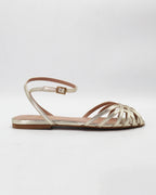 Shop the CIRA5 flat lattice sandal in gold calf leather. Italian-made with a woven strap detail, adjustable ankle strap, and rubber sole. Effortless metallic elegance.