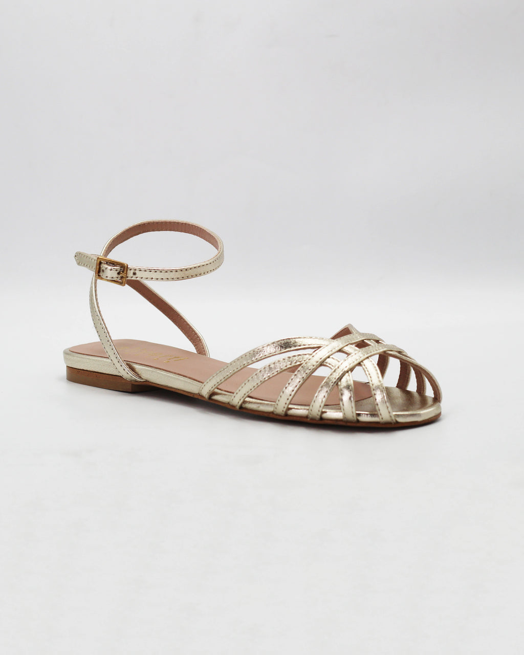Shop the CIRA5 flat lattice sandal in gold calf leather. Italian-made with a woven strap detail, adjustable ankle strap, and rubber sole. Effortless metallic elegance.