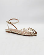 Shop the CIRA5 flat lattice sandal in gold calf leather. Italian-made with a woven strap detail, adjustable ankle strap, and rubber sole. Effortless metallic elegance.