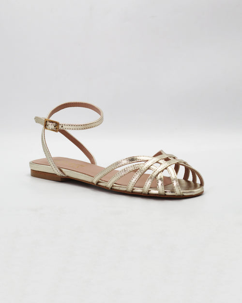 Shop the CIRA5 flat lattice sandal in gold calf leather. Italian-made with a woven strap detail, adjustable ankle strap, and rubber sole. Effortless metallic elegance.