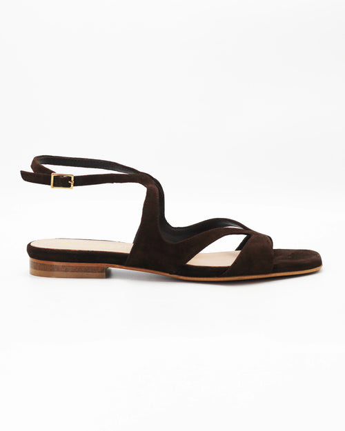 PATTY20 flat sandal in testa di moro suede with a sleek asymmetric toe strap and adjustable ankle strap. Handcrafted in Italy. Understated and easy.