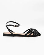 Shop the CIRA5 flat lattice sandal in black calf leather. Italian-made with a woven strap detail, adjustable ankle strap, and rubber sole. Classic summer elegance.