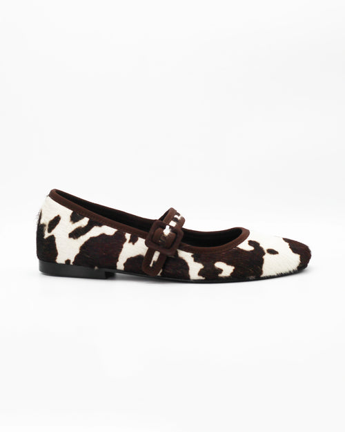 Shop the 6050 Mary Jane ballerina flat in brown cow-print calf hair. Italian-made with a buckle strap and rubber sole. Playful everyday elegance.