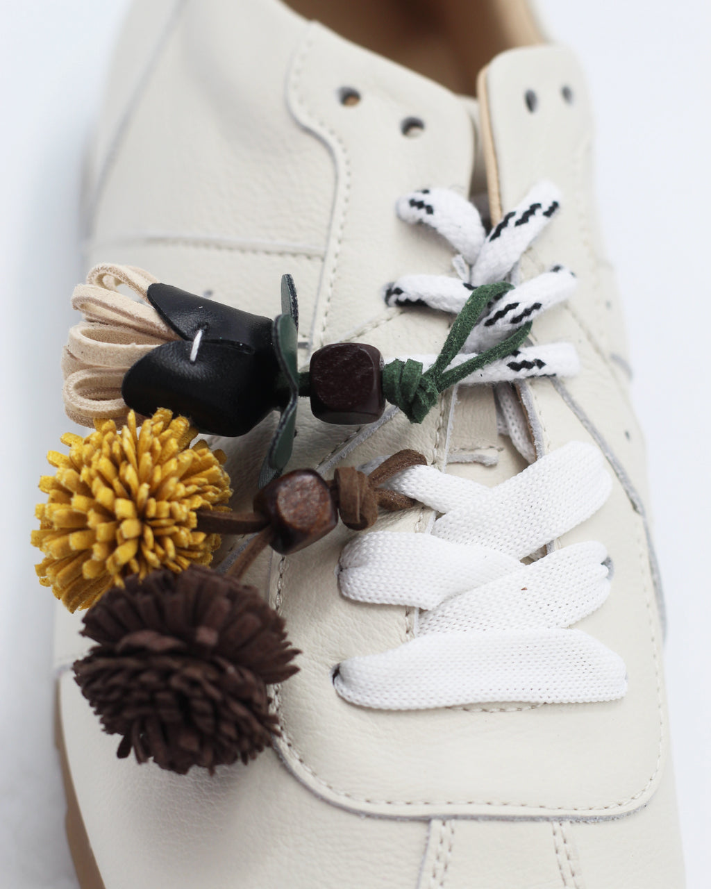Shop the 6066 leather sneaker in cream calf leather. Italian-made with playful floral charm details and a rubber sole. Casual everyday elegance.