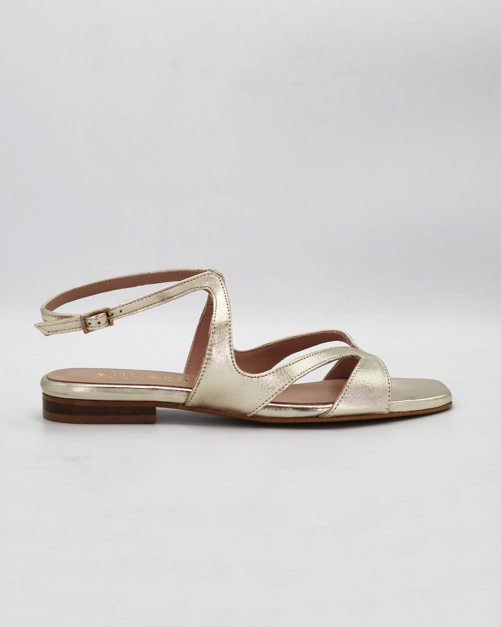 PATTY20 flat sandal in platino leather with a sleek asymmetric toe strap and adjustable ankle strap. Handcrafted in Italy. Understated and easy.