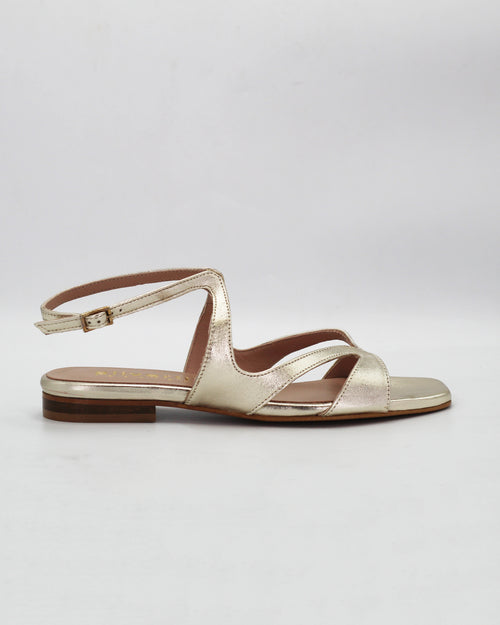 PATTY20 flat sandal in platino leather with a sleek asymmetric toe strap and adjustable ankle strap. Handcrafted in Italy. Understated and easy.